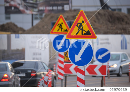 Roadworks warning traffic signs of construction work on city street and slowly moving cars 95970689