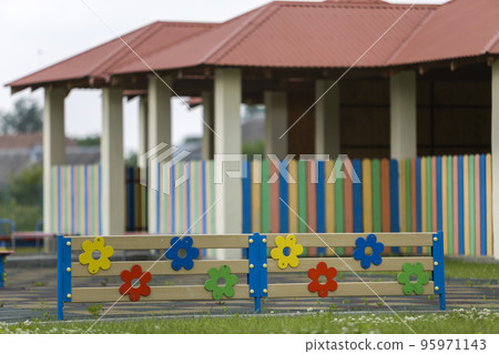 Multicolored wooden or plastic low decorative fence outdoors on sunny summer day. 95971143