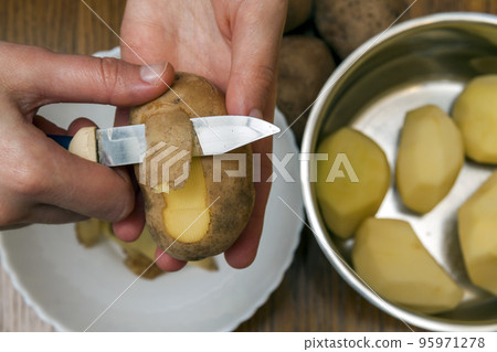 Detail of woman hands peeling fresh yellow potato with kitchen knife, Food preparation concept. Detail of woman hands peeling fresh yellow potato with kitchen knife, Food preparation concept. 95971278