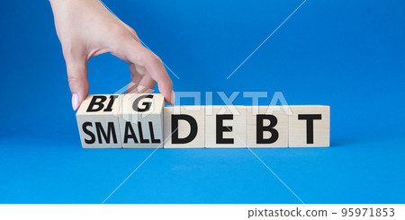 Big debt and small debt symbol. Businessman hand. Turned cubes with words Big debt and small debt. Beautiful blue background. Business concept. Copy space Big debt and small debt symbol. Businessman hand. Turned cubes with words Big debt and small debt. Beautiful blue background. Business concept. Copy space 95971853