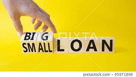 Big loan and Small loan symbol. Hand turns a cube and changes the word service Small loan to Big loan. Beautiful yellow background. Businessman hand. Busines concept. Copy space 95971898
