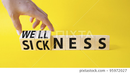 Wellness and Sickness symbol. Hand turns a cube and changes the word sickness to wellness. Beautiful yellow background. Businessman hand. Business and wellness and sickness concept. Copy space Wellness and Sickness symbol. Hand turns a cube and changes the word sickness to wellness. Beautiful yellow background. Businessman hand. Business and wellness and sickness concept. Copy space 95972027
