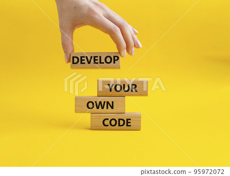 Develop your own code symbol. Concept words Develop your own code on wooden blocks. Businessman hand. Beautiful yellow background. Business and Develop your own code concept. Copy space. 95972072