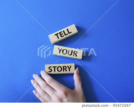 Tell your story symbol. Wooden blocks with words Tell your story. Beautiful blue background. Businessman hand. Business and Tell your story concept. Copy space. 95972097