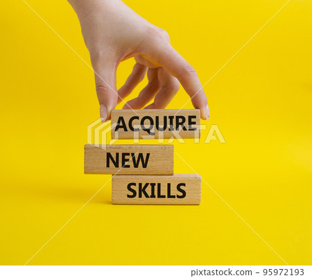 Acquire new skills symbol. Concept words Acquire new skills on wooden blocks. Beautiful yellow background. Businessman hand. Business and Acquire new skills concept. Copy space 95972193
