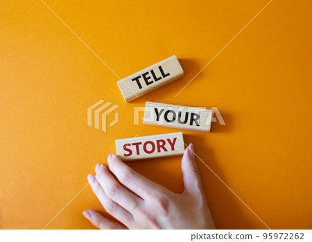 Tell your story symbol. Wooden blocks with words Tell your story. Beautiful orange background. Businessman hand. Business and Tell your story concept. Copy space. 95972262