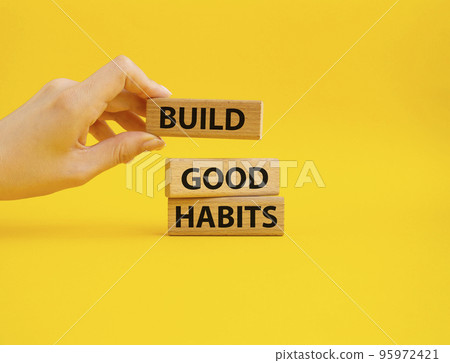 Build good habits symbol. Wooden blocks with words 'Build good habits'. Beautiful yellow background. Businessman hand. Business and 'Build good habits' concept. Copy space. Build good habits symbol. Wooden blocks with words 'Build good habits'. Beautiful yellow background. Businessman hand. Business and 'Build good habits' concept. Copy space. 95972421