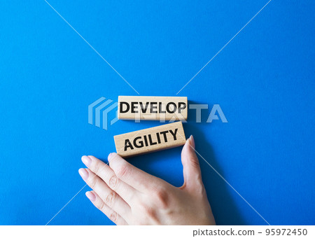 Develop agility symbol. Concept word Develop agility on wooden blocks. Beautiful blue background. Businessman hand. Business and Develop agility concept. Copy space Develop agility symbol. Concept word Develop agility on wooden blocks. Beautiful blue background. Businessman hand. Business and Develop agility concept. Copy space 95972450