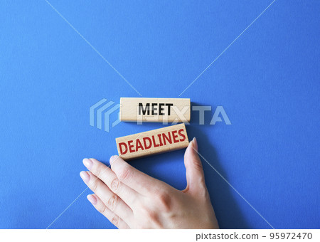 Meet Deadlines symbol. Concept word Meet Deadlines on wooden blocks. Businessman hand. Beautiful blue background. Business and Meet Deadlines concept. Copy space Meet Deadlines symbol. Concept word Meet Deadlines on wooden blocks. Businessman hand. Beautiful blue background. Business and Meet Deadlines concept. Copy space 95972470