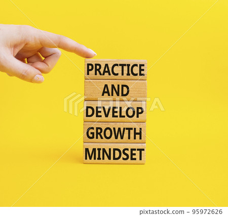 Practice and Develop growth mindset symbol. Wooden blocks with words Practice and Develop growth mindset. Beautiful yellow background. Businessma hand. Business concept. Copy space 95972626
