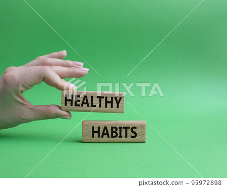 Healthy habits symbol. Concept word Healthy habits on wooden blocks. Beautiful green background. Businessman hand. Business and Healthy habits concept. Copy space 95972898