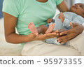mother's hand holding little feet newborn baby's in her palm. 95973355
