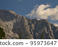 Paraglider flies in front of a massive rock wall 95973647
