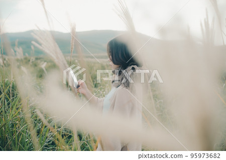 一個女人在大自然中拿著智能手機的照片 95973682