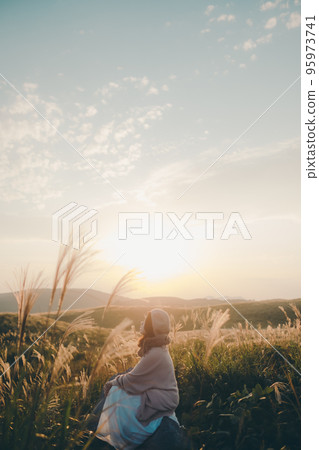 Photo of a woman standing in nature at sunset Photo of a woman standing in nature at sunset 95973741