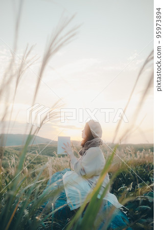 日落時在大自然中讀書的女人的照片 95973894