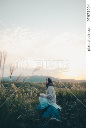 Photo of a woman reading in nature at sunset Photo of a woman reading in nature at sunset 95973904