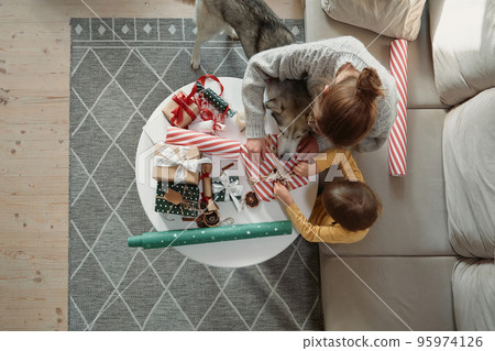 Family mother child and pet dog having fun and decorating christmas gifts together, top view Family mother child and pet dog having fun and decorating christmas gifts together, top view 95974126