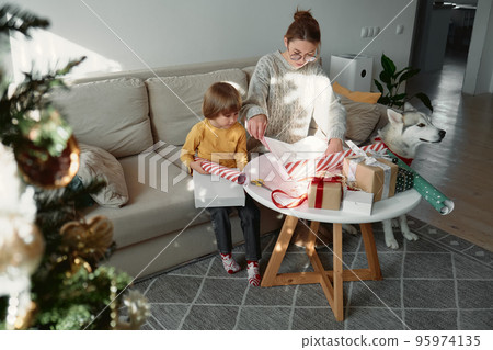 Decorating Christmas gifts, family mother, child and pet dog wrapping Christmas gift box together 95974135