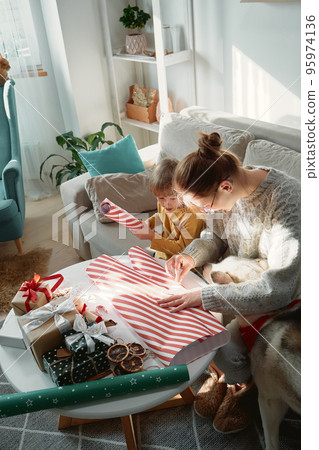 Decorating Christmas gifts, family mother, child and pet dog wrapping Christmas gift box together 95974136