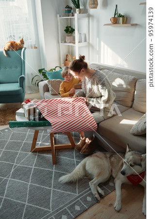 Wrapping and decorating Christmas gifts, family mother, child and pets together 95974139