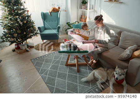 Wrapping and decorating Christmas gifts, family mother, child and pets together 95974140