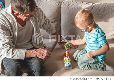 Elderly grandpa or grandfather plays with his little grandson Elderly grandpa or grandfather plays with his little grandson 95974174