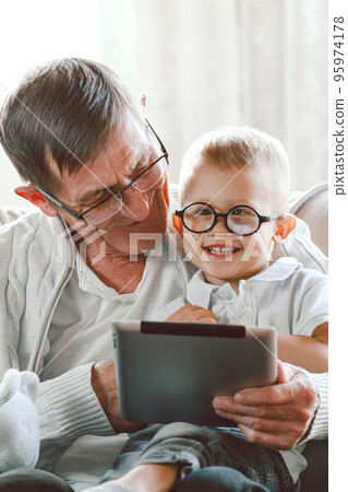 Elderly grandfather and his little grandson use a tablet device Elderly grandfather and his little grandson use a tablet device 95974178