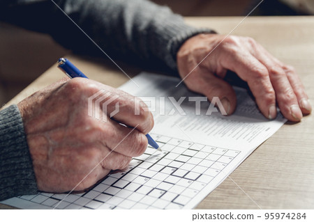 Senior solves sudoku or a crossword puzzle to slow the progressi Senior solves sudoku or a crossword puzzle to slow the progressi 95974284