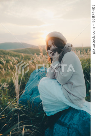 Photo of a woman standing in nature at sunset 95974403