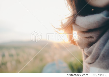 Photo of a woman standing in nature at sunset 95974412