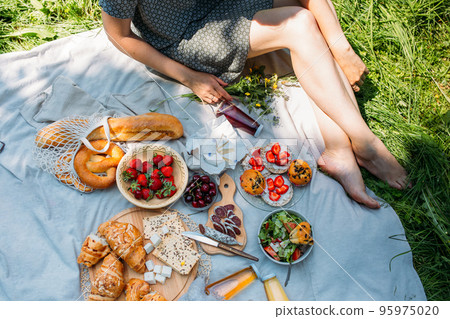Beautiful woman on picnic. She smiles, eats strawberries and enjoys summer. Beautiful woman on picnic. She smiles, eats strawberries and enjoys summer. 95975020