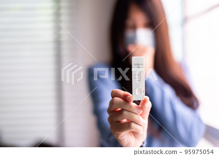 Woman patient holding positive test result for coronavirus or covid 19 at home 95975054