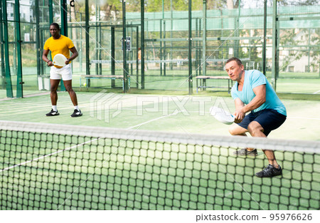 European man padel tennis player trains on the court European man padel tennis player trains on the court 95976626