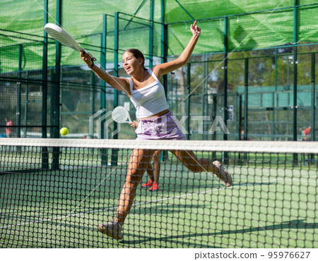 Active womans with enthusiasm playing padel on tennis court 95976627