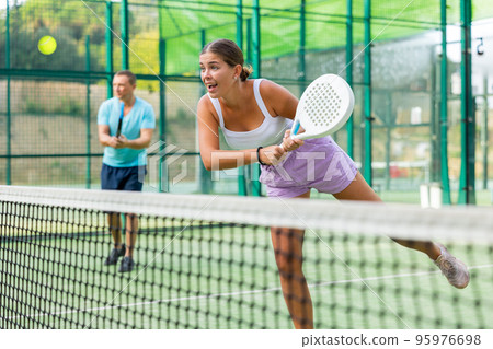 Girl playing padel tennis match during training on court Girl playing padel tennis match during training on court 95976698