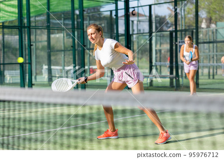European woman padel tennis player trains on the outdoor court 95976712