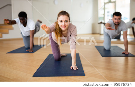 Woman practicing Dandayamna Bharmanasana during group yoga training Woman practicing Dandayamna Bharmanasana during group yoga training 95976724