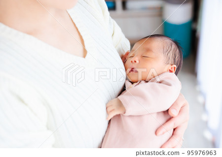 Newborn baby sleeping in mom's arms 95976963