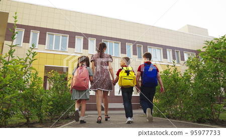 teacher with children first grade. mom leads happy children school holding hands. group children student with mother parent. happy family. classmates with school backpacks. happy family concept. teacher with children first grade. mom leads happy children school holding hands. group children student with mother parent. happy family. classmates with school backpacks. happy family concept. 95977733