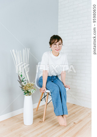 戴眼鏡的日本女人坐在房間的椅子上 95980650