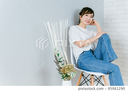Japanese woman in fashionable jeans sitting on a chair and thinking Japanese woman in fashionable jeans sitting on a chair and thinking 95981290