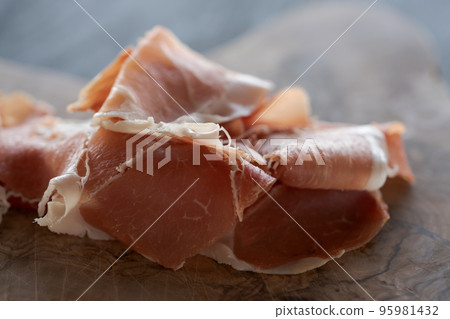 Thin slices of jamon on olive wood board Thin slices of jamon on olive wood board 95981432