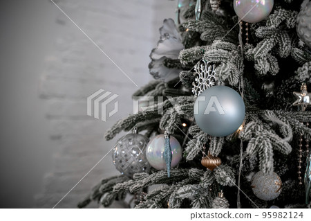 Close-up of a festively decorated outdoor Christmas tree with balls on a blurred sparkling fairy background. Defocused garland lights, bokeh effect. Close-up of a festively decorated outdoor Christmas tree with balls on a blurred sparkling fairy background. Defocused garland lights, bokeh effect. 95982124