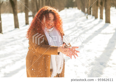 Fat caucasian woman playing snowballs in the park.  95982611