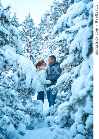 A joyful couple in love walking in winter forest heavy covered with snow A joyful couple in love walking in winter forest heavy covered with snow 95983715