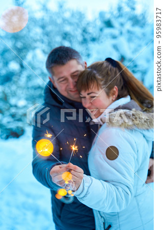 A young couple in love embracing in the winter woods holding sparklers. A festive winter fairy tale. A walk through a snow-covered forest A young couple in love embracing in the winter woods holding sparklers. A festive winter fairy tale. A walk through a snow-covered forest 95983717