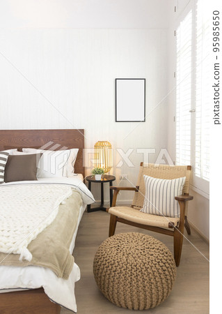 Stylish bedroom interior with wooden bed, furniture, flowers in vase, rattan decoration and elegant accessories. Beautiful bed sheets, blanket and pillows. Cozy home decor. 95985650