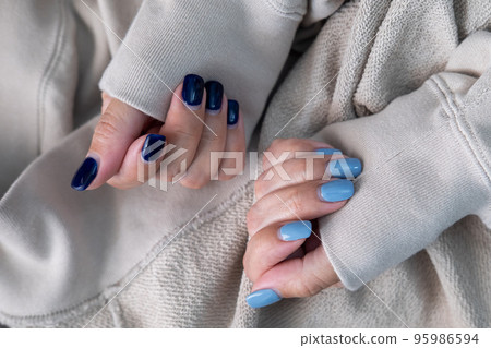 Gel nail design.Beautiful manicure. Nail polish is applied to the hand, polish is a blue color. Blue background closeup. Multi-colored blue manicure. 95986594