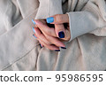 Gel nail design.Beautiful manicure. Nail polish is applied to the hand, polish is a blue color. Blue background closeup. Multi-colored blue manicure. 95986595